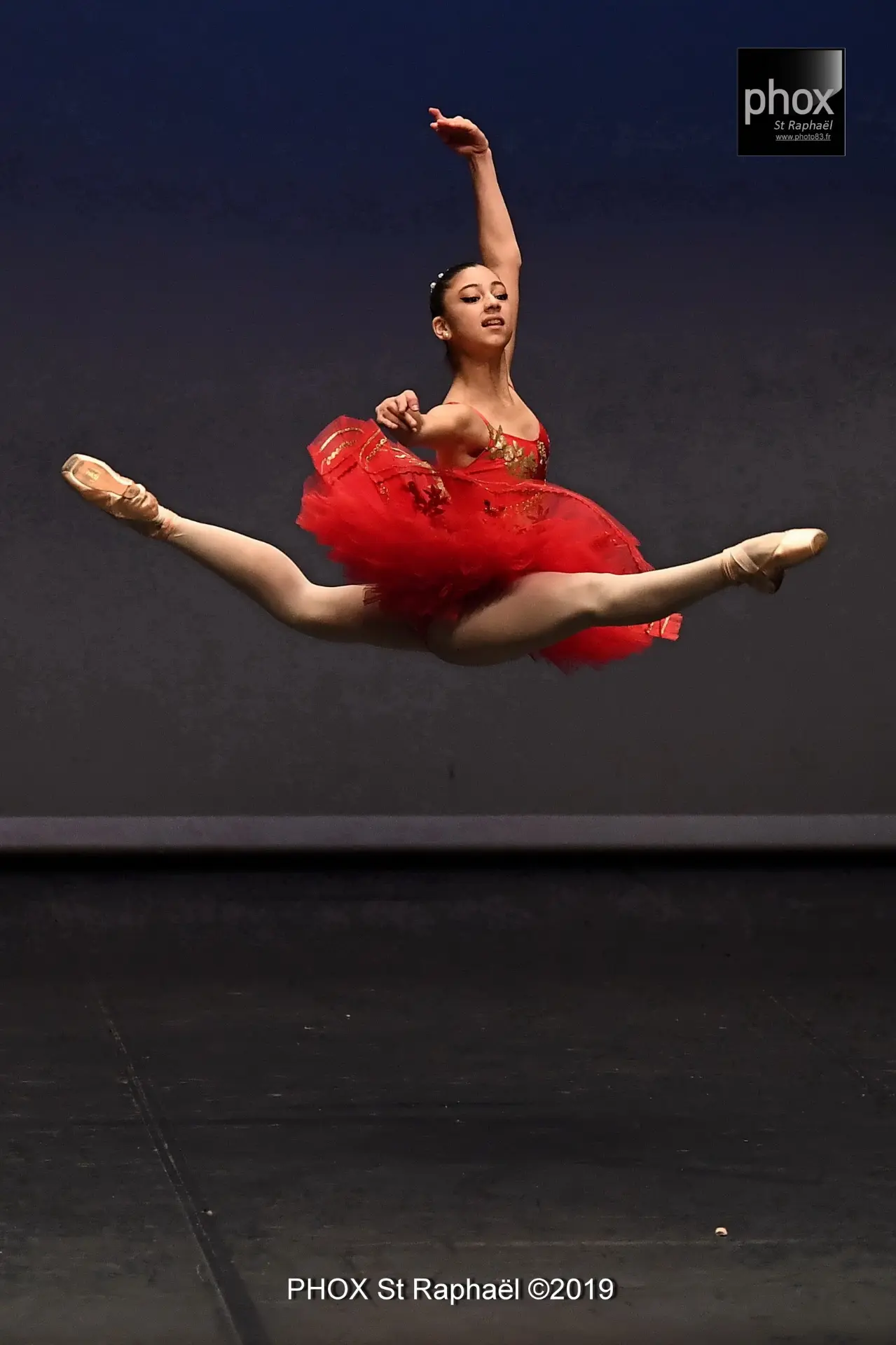 Danseuse classique en tutu rouge sur pointes en scène